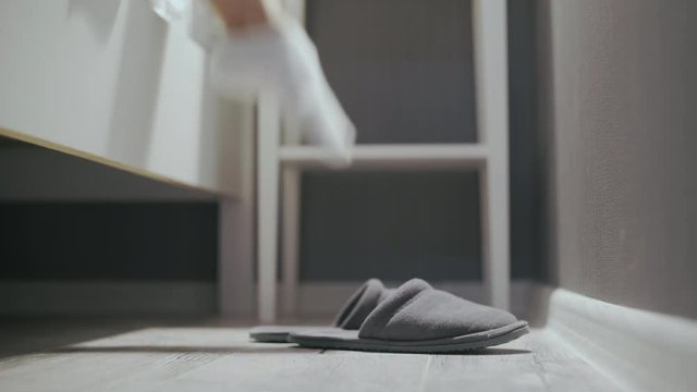 Woman takes off grey slippers and goes to sleep