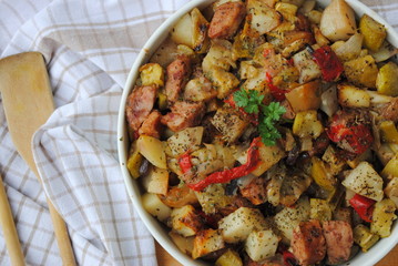 Roasted Vegetable and Sausage Casserole with fresh parsley leaf in the middle, served in a white ceramic bowl. Top view.