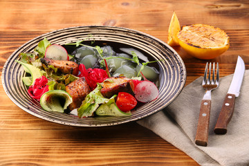 zander salad with vegetables in plate on wooden table. lemon for fish and beer lunch