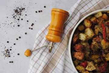 Roasted Vegetables and Sausages Casserole. Pepper mill and peppercorns decoration. Top view.