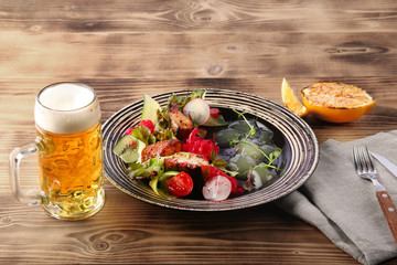 zander salad with vegetables in plate on wooden table. lemon for fish and beer lunch