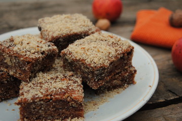 Apple Pie Slices sprinkled with ground walnuts, in a white plate on a wooden background.