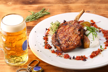freshly grilled hot steaks with potato on wooden table and beer in glass