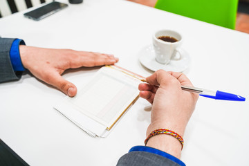 Hands with office supplies on work table with pen, tea and writing paper and decoration with sunglasses on the table.