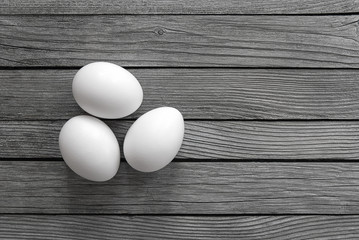 three white eggs on gray wooden background