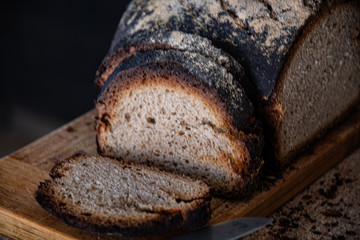 Cooking at home. Homemade rustic bread on a cutting kitchen board, on wooden background.