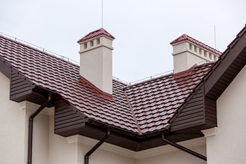 a roof top of a brown ceramic tile with ventilation by a pipe a storm drainage system, close up details of the architectural structure.