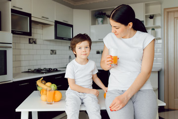 Little boy and mother play with fruits and fool around. They are wearing t-shirts