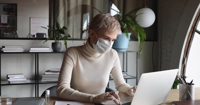 Sick ill businesswoman wears medical mask, gloves, coughing working from home office on quarantine using laptop. Female remote worker having coronavirus infection symptom prevents covid 19 spreading.