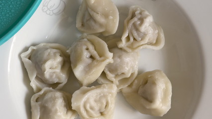 child hand placing cooked meat dumplings on plate