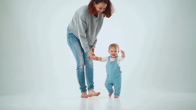 Mom holds the baby by the hand and teaches to walk. studio slow motion