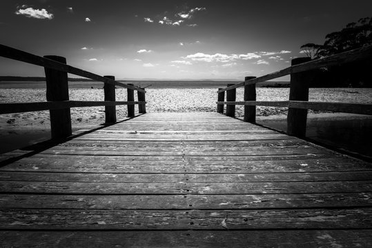 Black and white photo of a wooden bridge to the ocean, Jervis Bay Australia