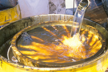 Workers pouring toxic wastes into a metal drum at waste cleanup site on Earth Day at the Unocal plant in Wilmington, Los Angeles, CA