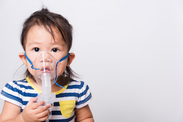 Closeup Asian face, Little baby girl sick her using steam inhaler nebulizer mask inhalation oneself