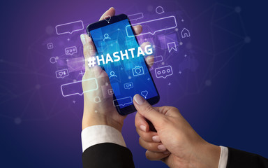 Female hand typing on smartphone with #HASHTAG inscription, social media concept