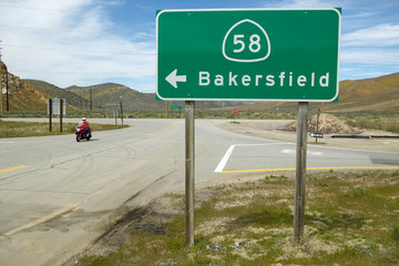 A motorcycle driving past a road sign pointing to Route 58 near Bakersfield CA