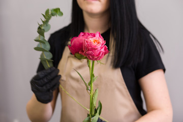 florist in black gloves creates a bouquet of red peonies