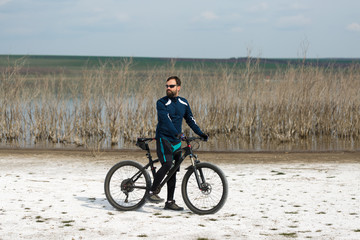 Cyclist in pants and fleece jacket on a modern carbon hardtail bike with an air suspension fork. .A guy with a bicycle on a salt lake.