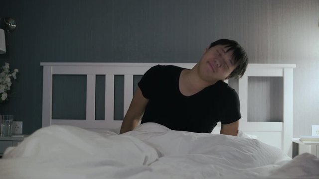 Young asian man wakes up and got out of bed