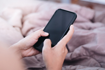 Close up young woman using smartphone on bed