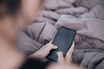 Close up young woman using smartphone on bed