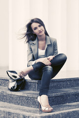 Happy young fashion woman in gray blazer sitting on steps