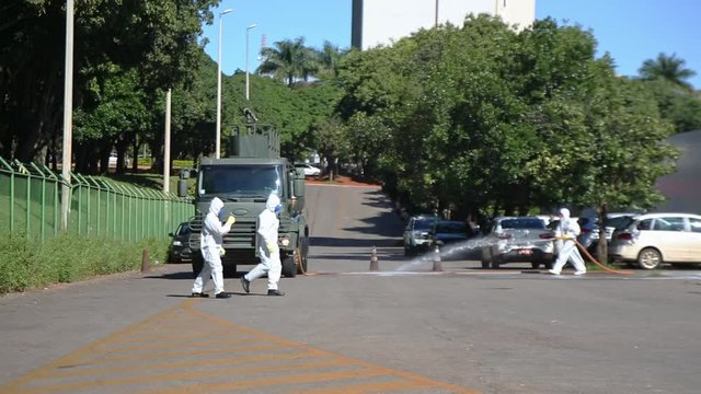 Brazilian Military Personnel Cleanse The Road Outside A Hospital After COVID-19 Contamination. Wide Shot.