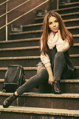 Happy young fashion woman in gray sleeveless coat and light pink sweater