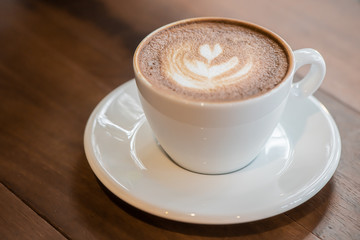 A Cup of art latte or cappuccino coffee on wood table