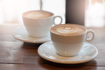 two cup of art latte or cappuccino coffee on wood table