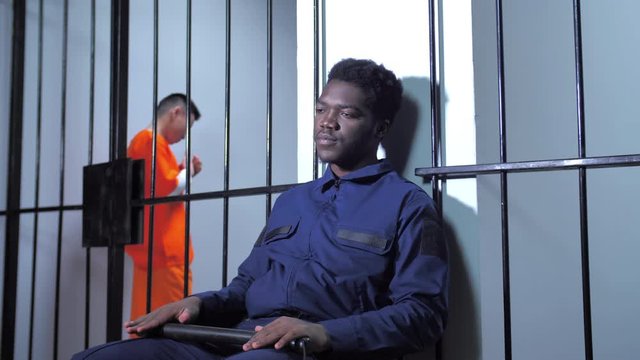 Black jailer sits in the prison corridor