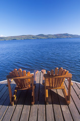 Fototapeta na wymiar Two Adirondack chairs on a deck overlooking Lake George, NY