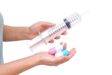Female hand holding two big capsule medicine and a big syringe islated on white background / Drug overdose concept