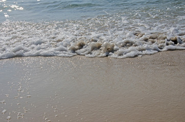 White sponges of waves on sand beach