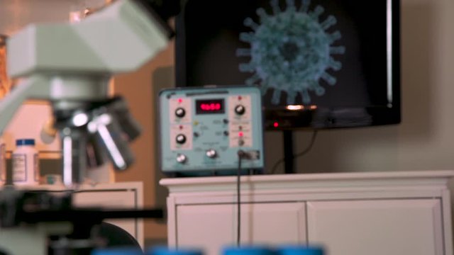 Scene tilts from lab equipment and other paraphernalia used to research a vaccine for the coronavirus COVID19 to an image on a monitor of the virus.