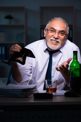 Old male employee working late in the office