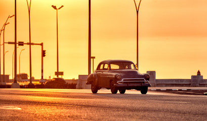 old classic american car driving though the streets of havana in cuba with the malecon in the background - 335702226
