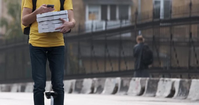 Express pizza delivery in the city. A courier in a yellow T-shirt to rides on a gyro board with a stack of ready-made pizza.