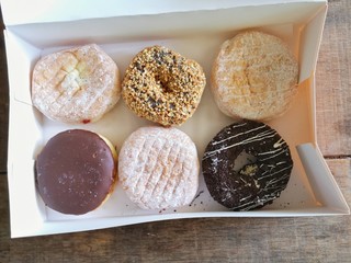 Donuts are arranged in a white paper box.