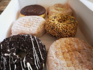 Donuts are arranged in a white paper box.