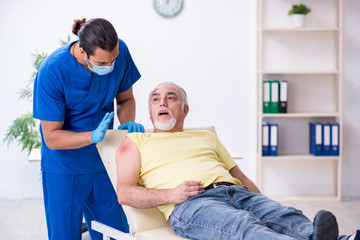 Fototapeta premium Injured old man visiting young male doctor traumatologist