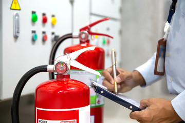 Engineer are checking and inspection a red fire extinguishers in the fire control room for safety prevention and fire training.