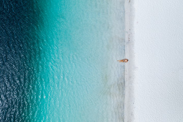 Beautiful girl lying on white sand on a stunning beach with blue crystal clear water at Lake Mckenzie Fraser Island Australia