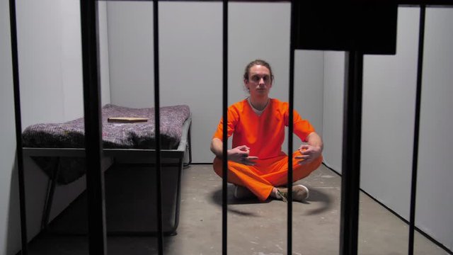 Prisoner meditates behind prison bars
