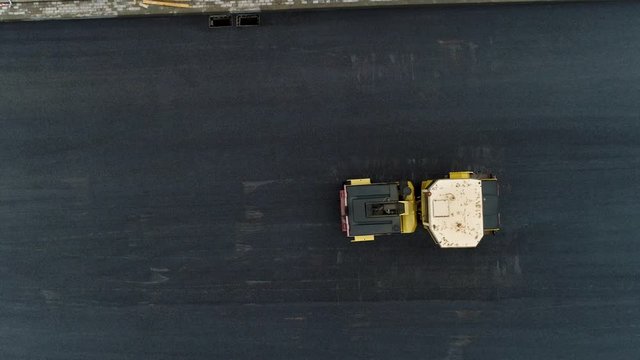 A yellow paver flatten new hot asphalt. Build new road. Arial drone shot.