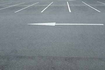 A large white arrow painted on the ground showing the way in an empty car park