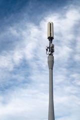 Modern cell phone tower against a blue sky with white clouds.
