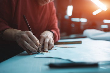 man shaping leather for shoe with knife on factory