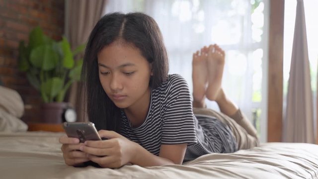 peer pressure. young teenage asian girl feel depress while using her mobile phone at home