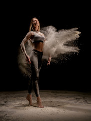 Young woman dancing in dust cloud shot